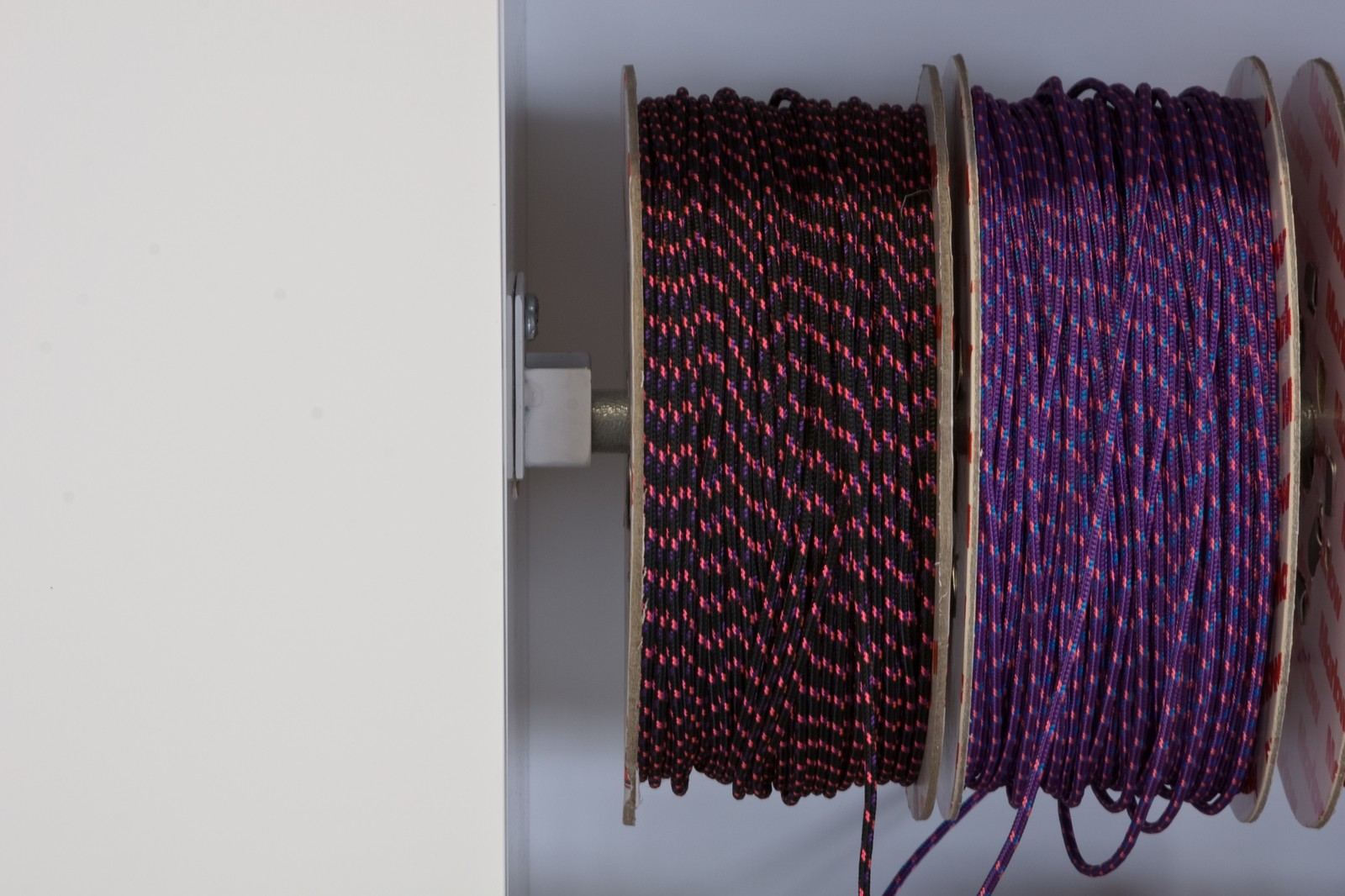 Detail van twee touwspoelen bevestigd aan de witte kastwand.