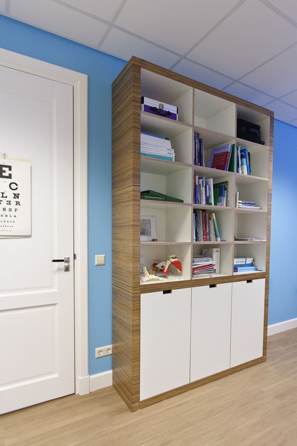 Stellingkast met open vakken vol boeken boven een rij gesloten kastdeuren.