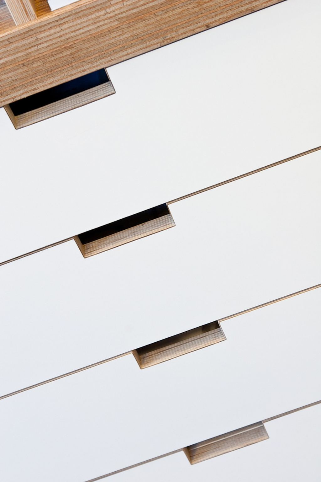 Detail van de lades met houten inzetgrepen van de kastenwand.