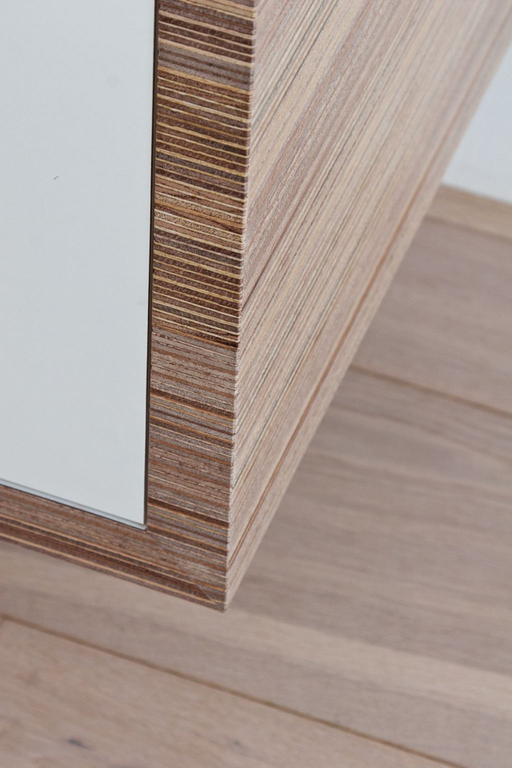 Detail van de plexwood hoekverbinding op een witte kastdeur.