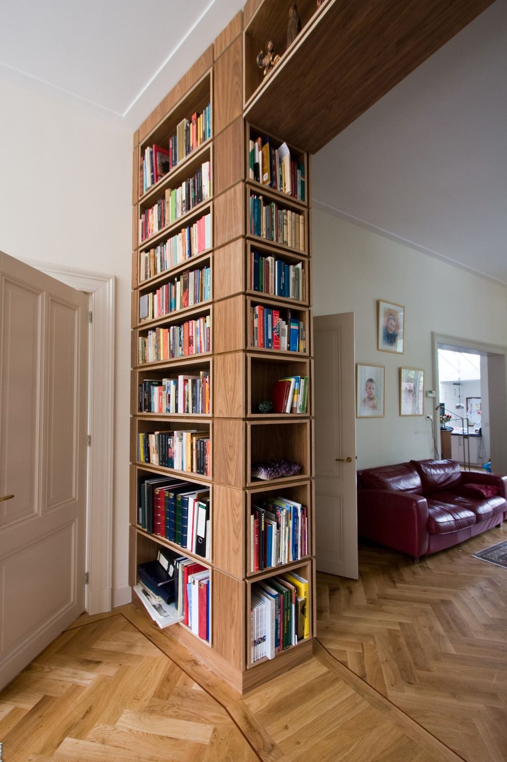 Wandvullende boekenkast die als kolom tussen twee kamers dient.