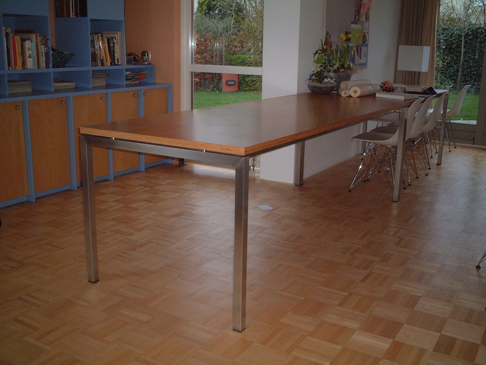 Lange eettafel met een multiplex blad op een stalen onderstel.