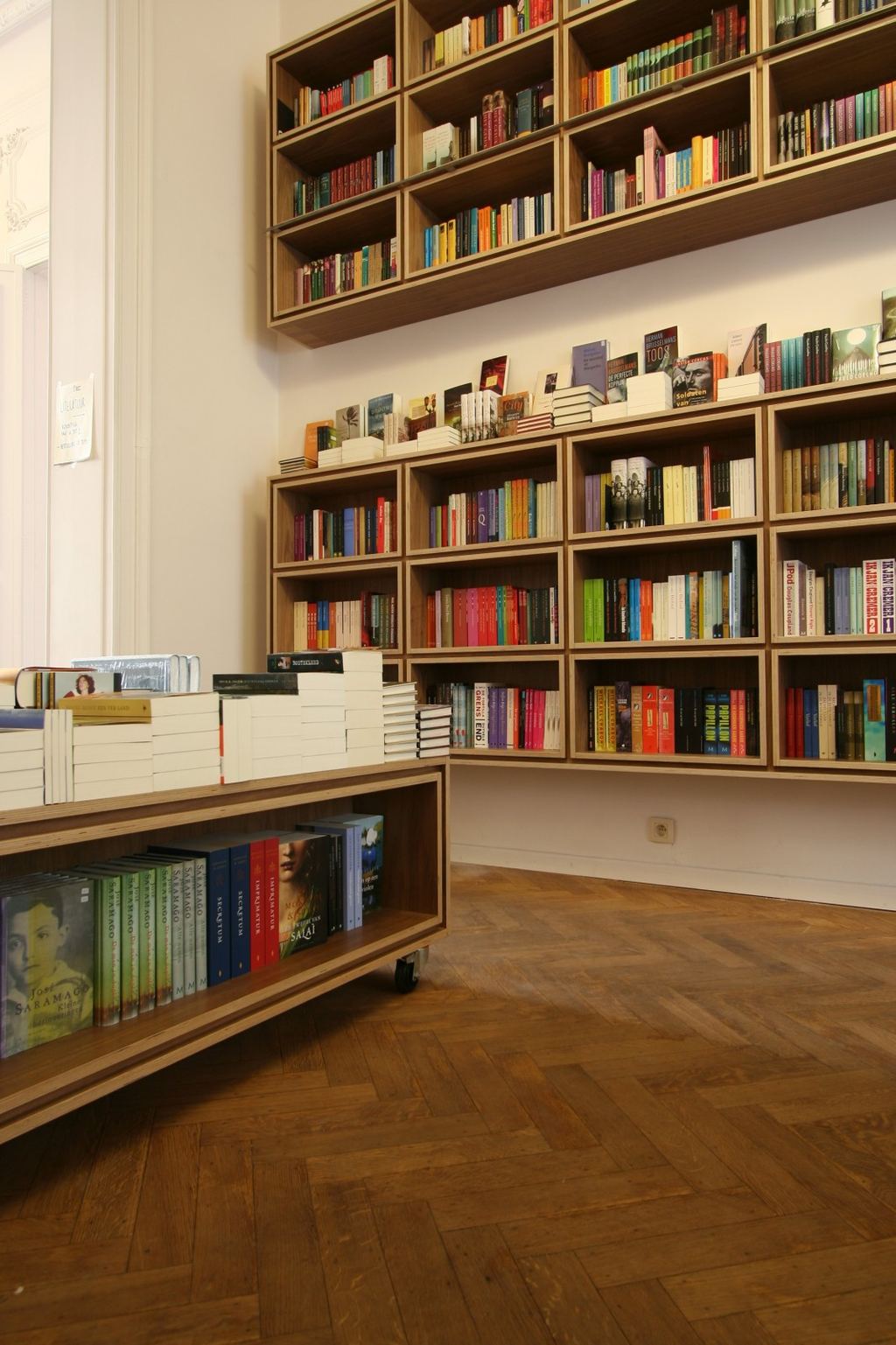 Verrijdbare boekentafel op wielen voor een wandvullende boekenkast.