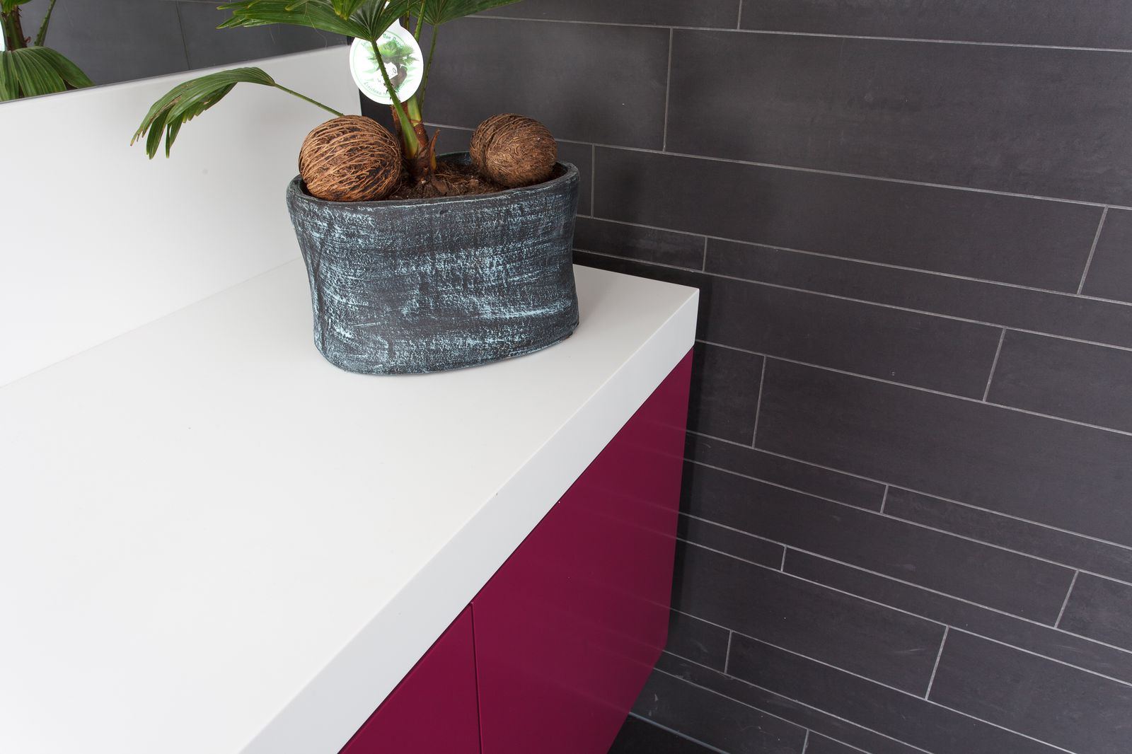 Detail van de hoek van het witte werkblad, boven een kastfront in magenta.