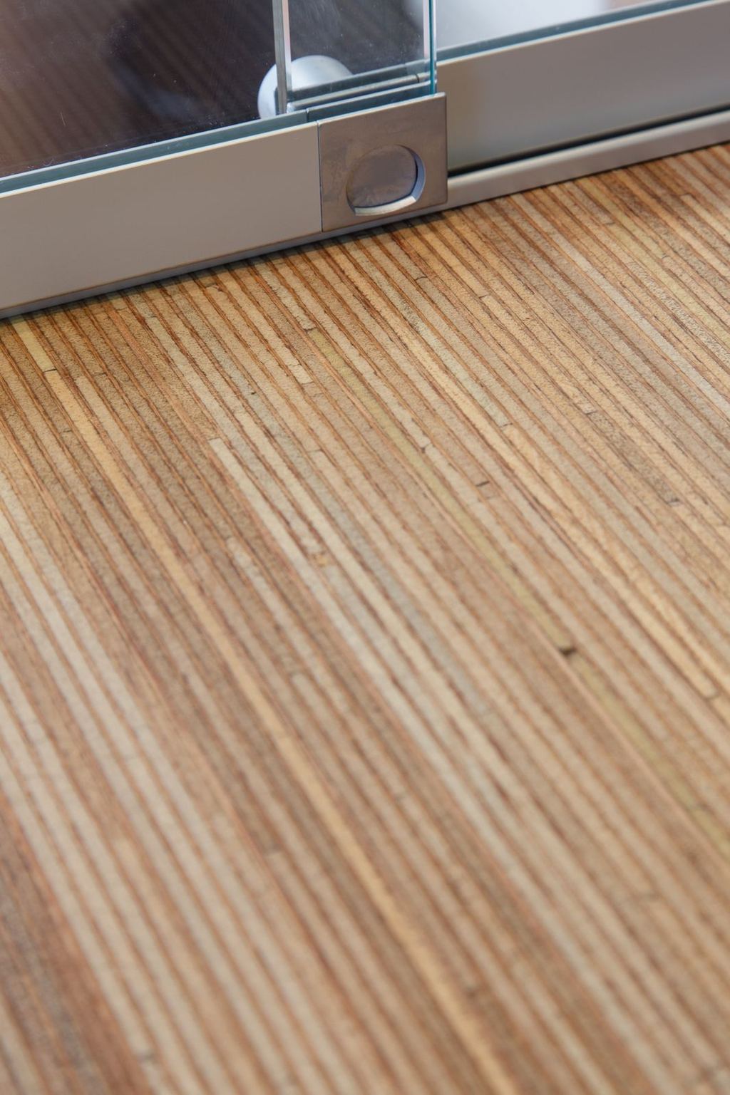 Detail van de balie in meranti plexwood, met rail voor een glazen wand.