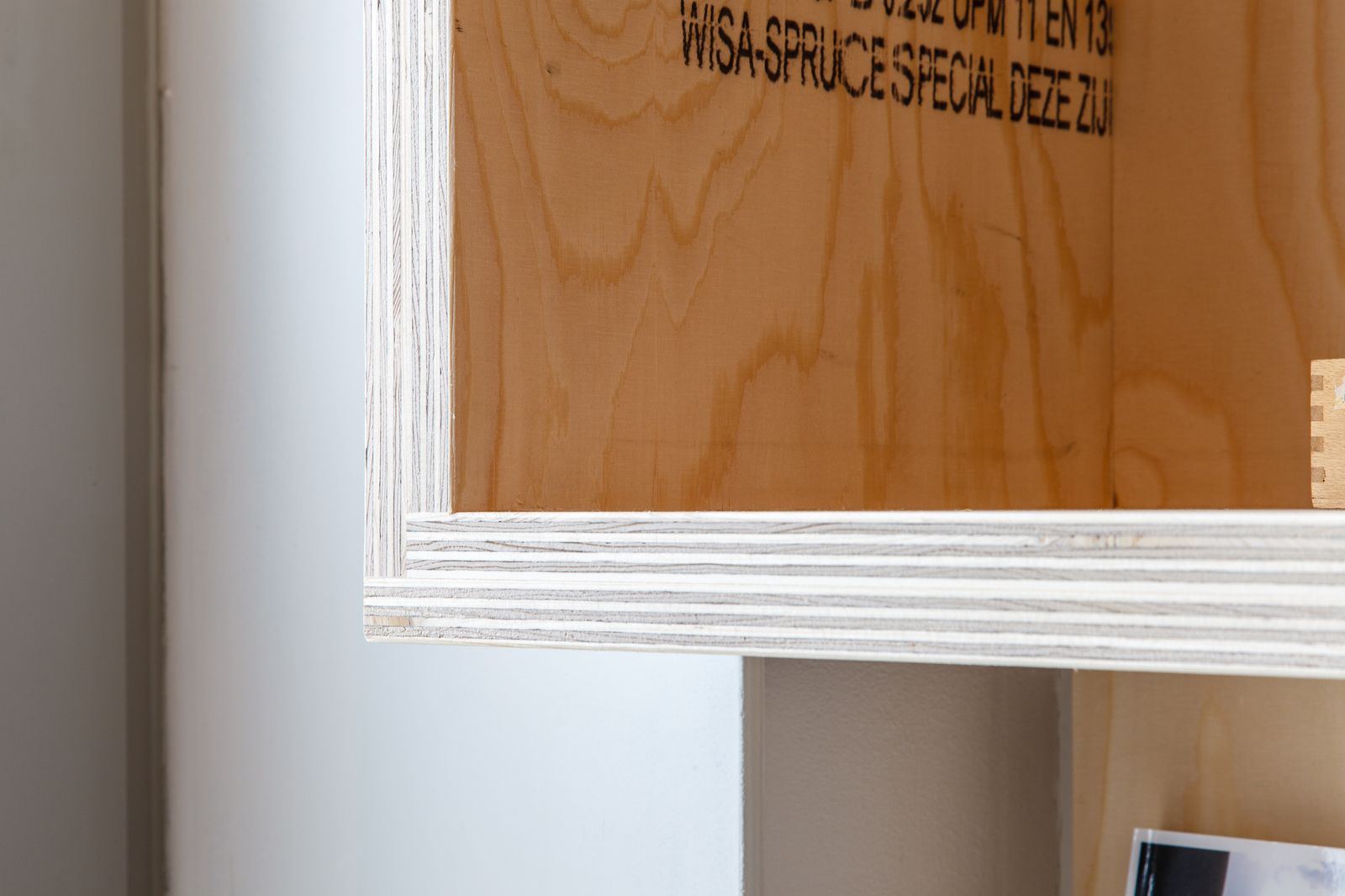 Detail van de houtnerf en fabrieksstempel op het vuren paneel.