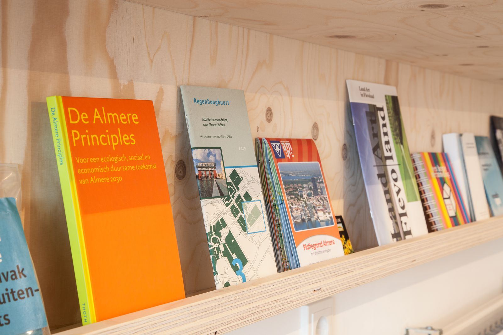 Boeken en brochures naast elkaar op een vuren plank.