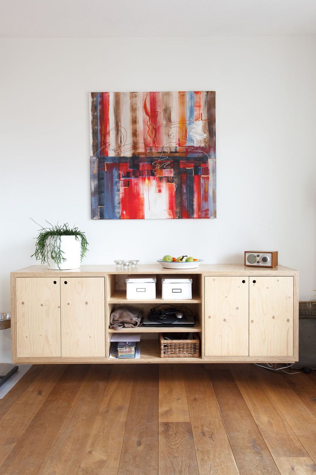 Zwevend dressoir van hout, met open vakken in het midden en gesloten deuren aan weerszijden.