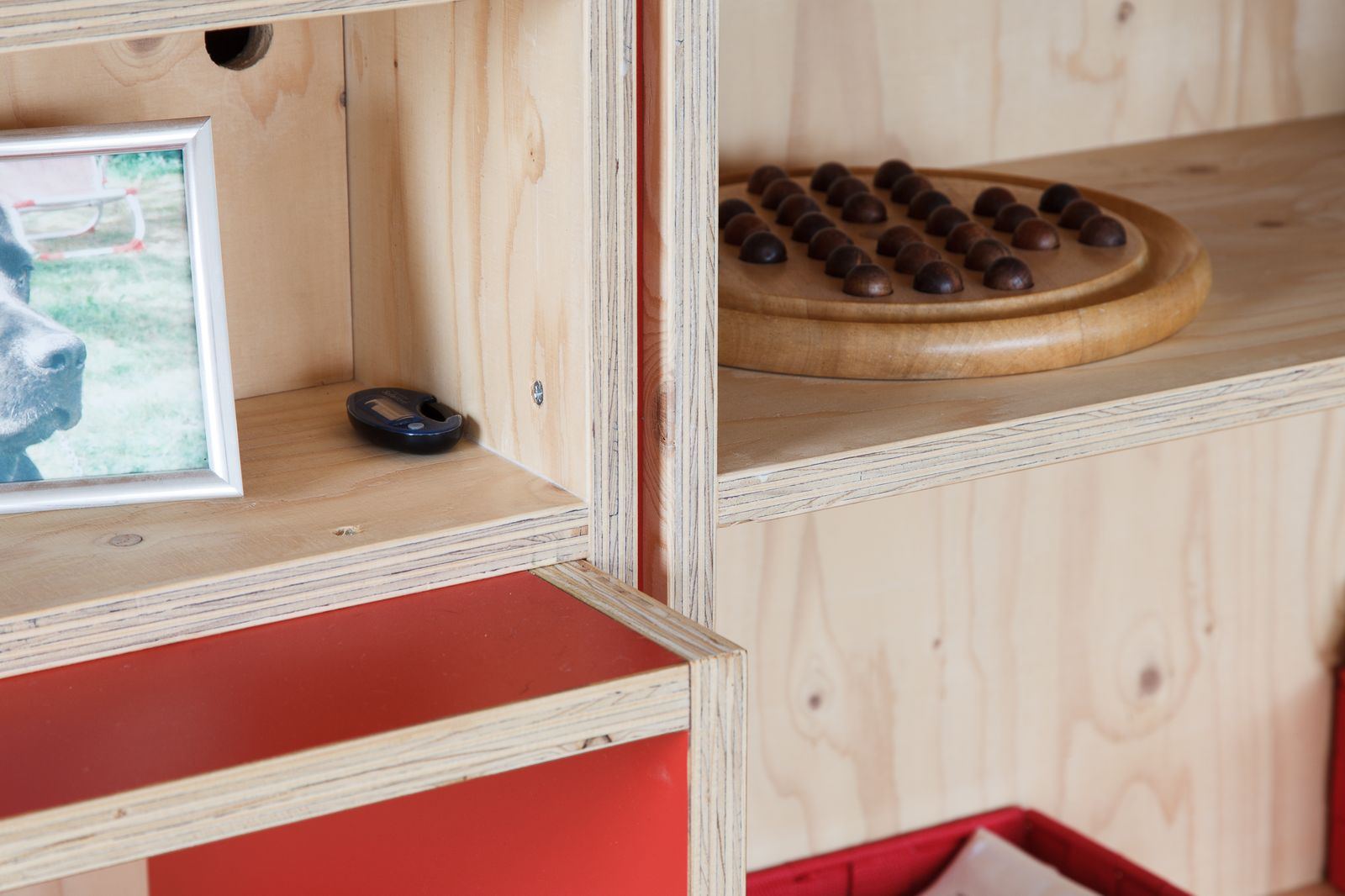 Open houten kastvak met een fotolijst, naast een plank met een houten bordspel.
