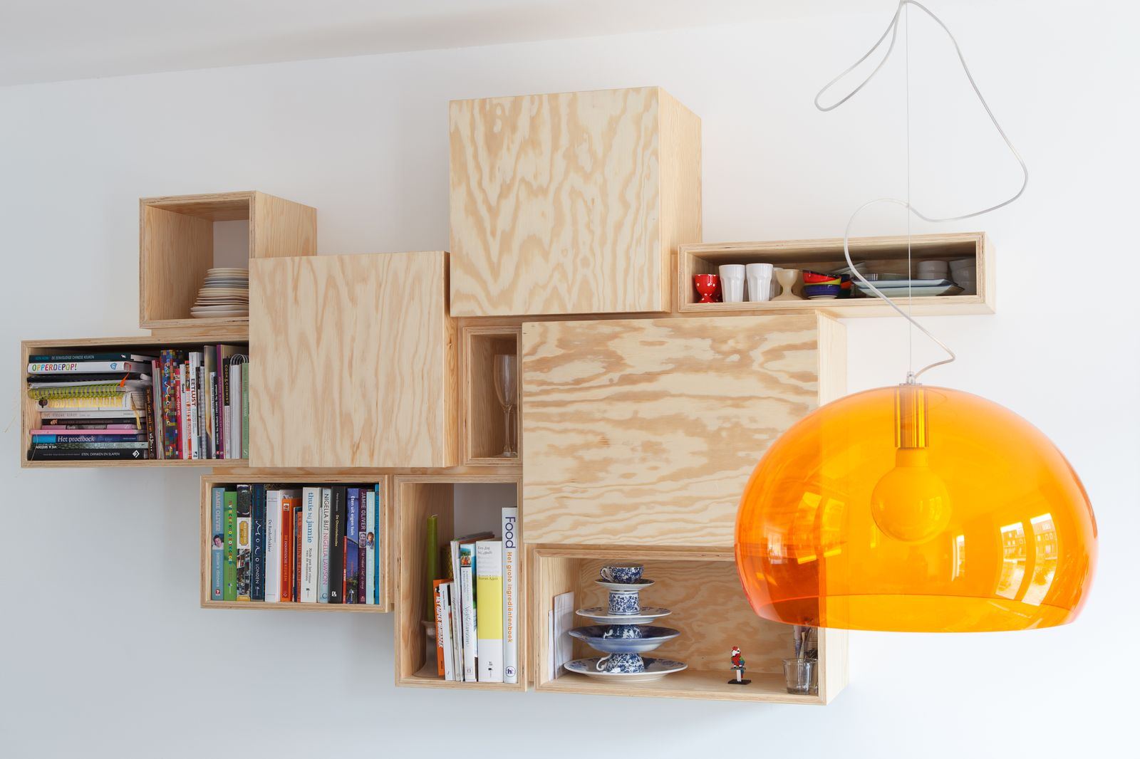 Wandkast opgebouwd uit een stapeling van grenen multiplex kastjes.