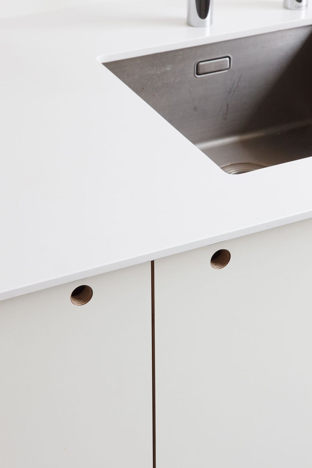 Detail van het corian werkblad met verzonken greepgaten in de fronten.
