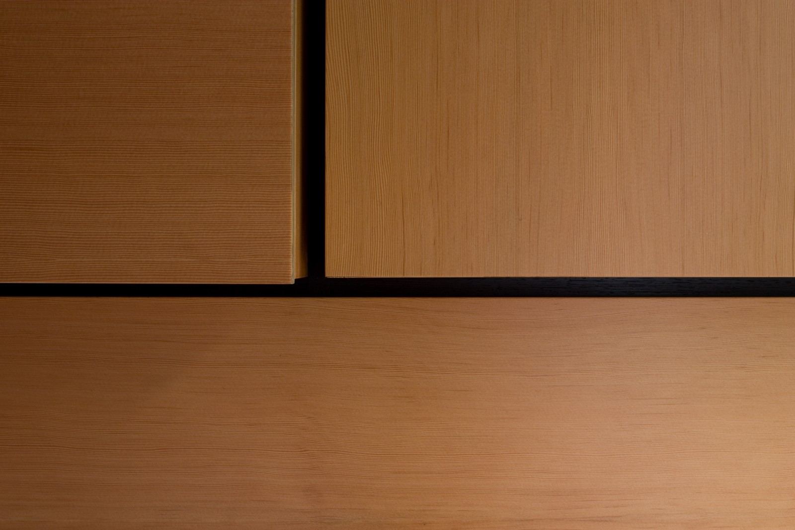 Detail van de naad tussen twee kastdeuren, met een zwarte inleg ertussen.