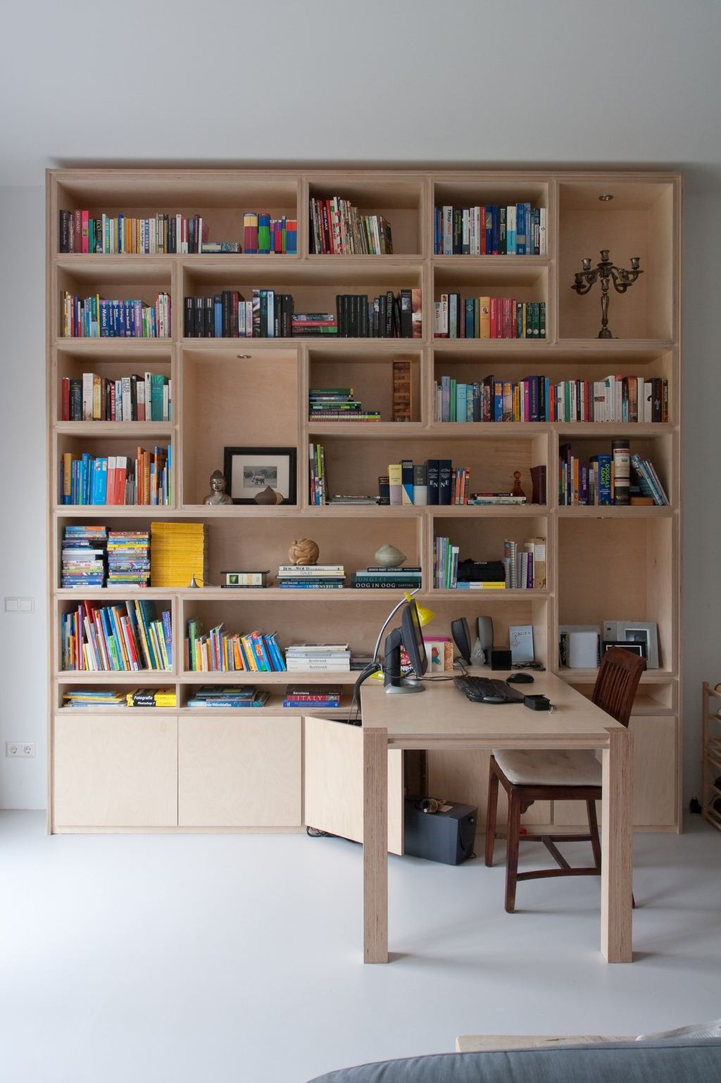 Boekenkast met een tafel geïntegreerd aan de onderzijde, ervoor een houten stoel.