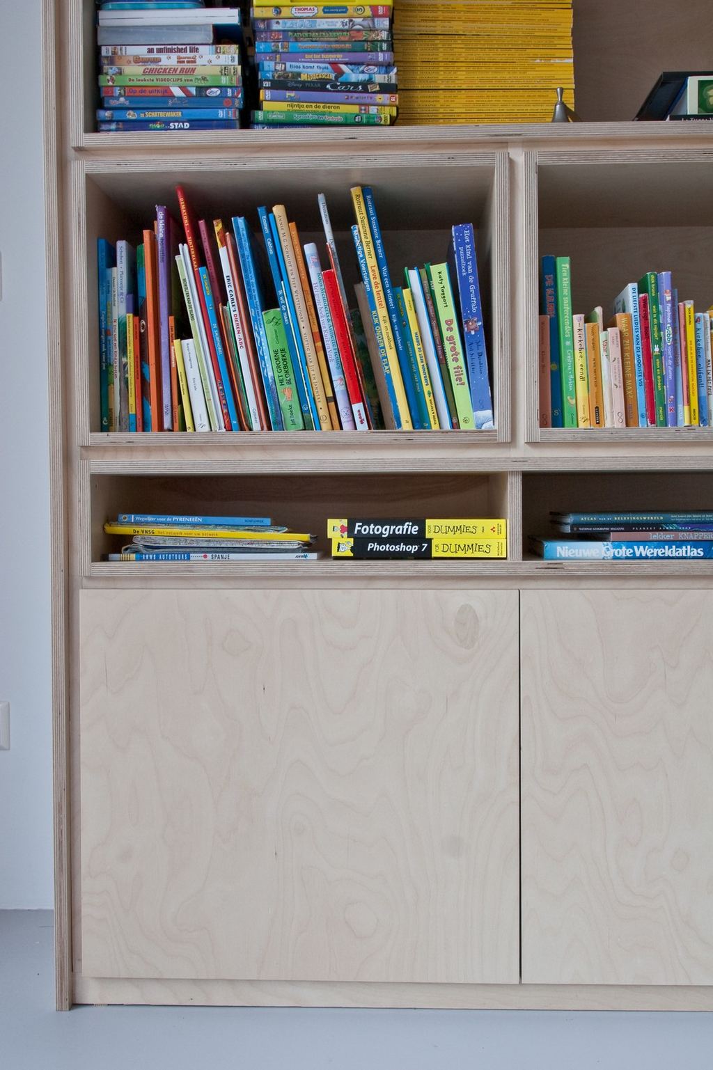 Vakken met kinderboeken boven gesloten kastdeuren.