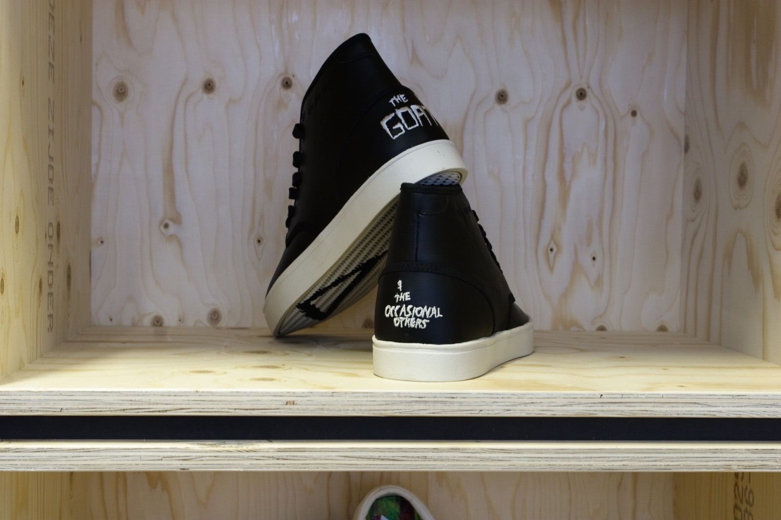 Detail van een vuren multiplex insteekvak met een paar sneakers erin.