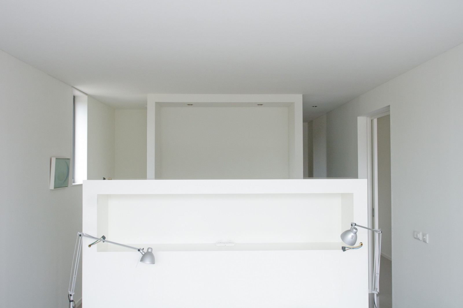 Wit spuitwerk kastwand met een nis, gebruikt als room divider.