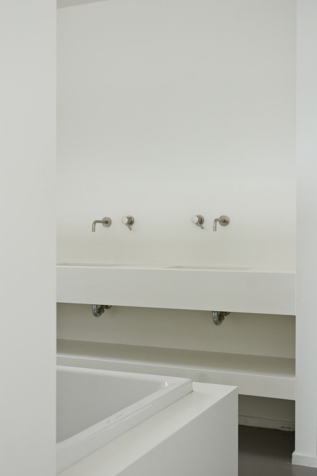 Wastafelmeubel in wit spuitwerk met een open legplank eronder.