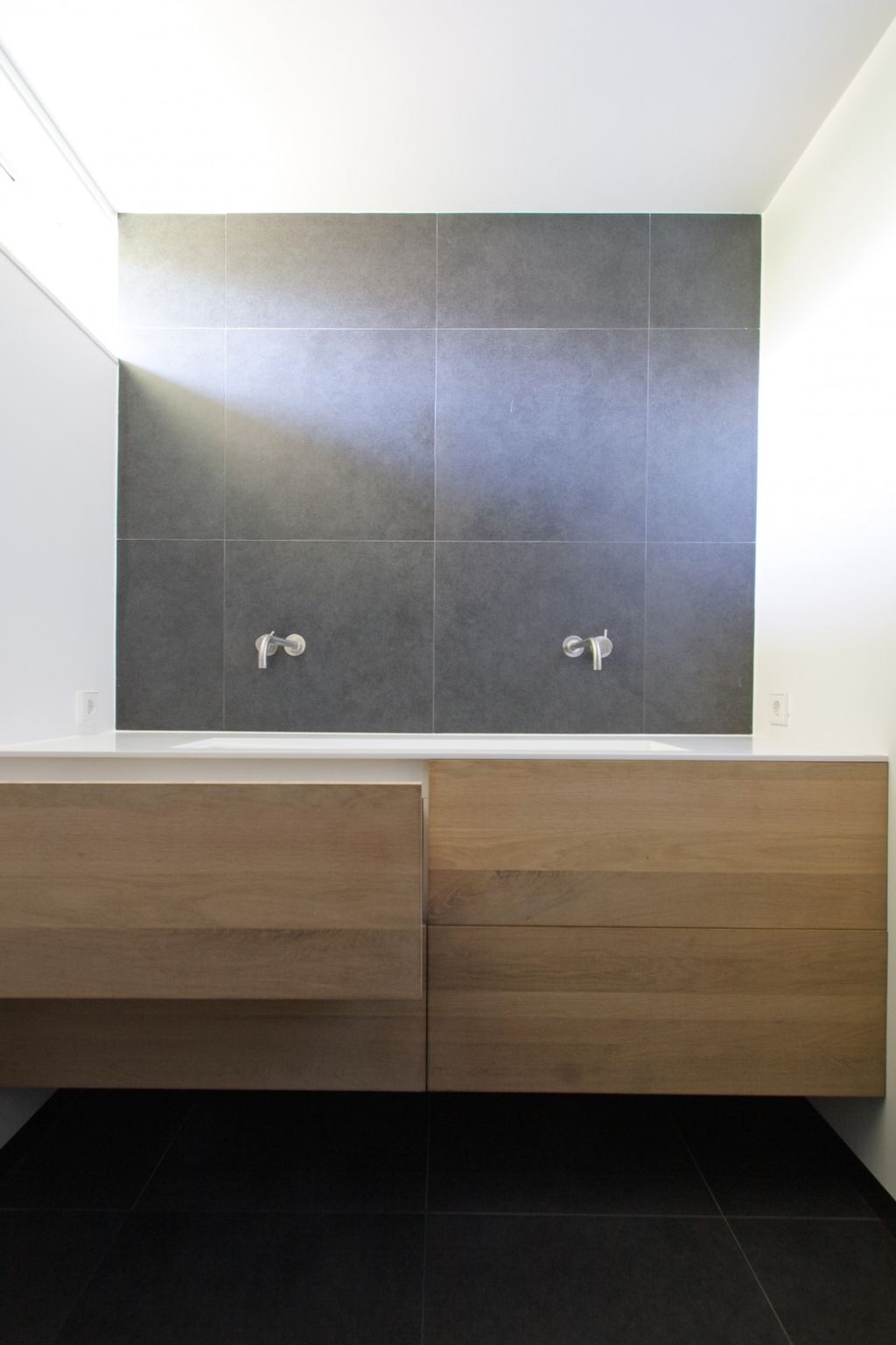 Badkamermeubel met kersen lades en een vlakke corian wastafel.