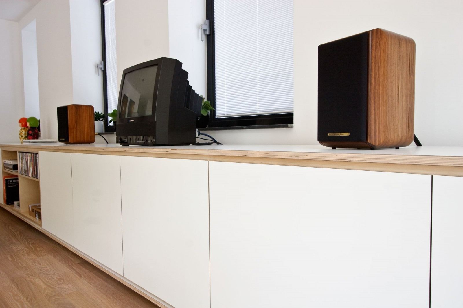 Wit dressoir onder de vensterbank met een open plank voor cd's.