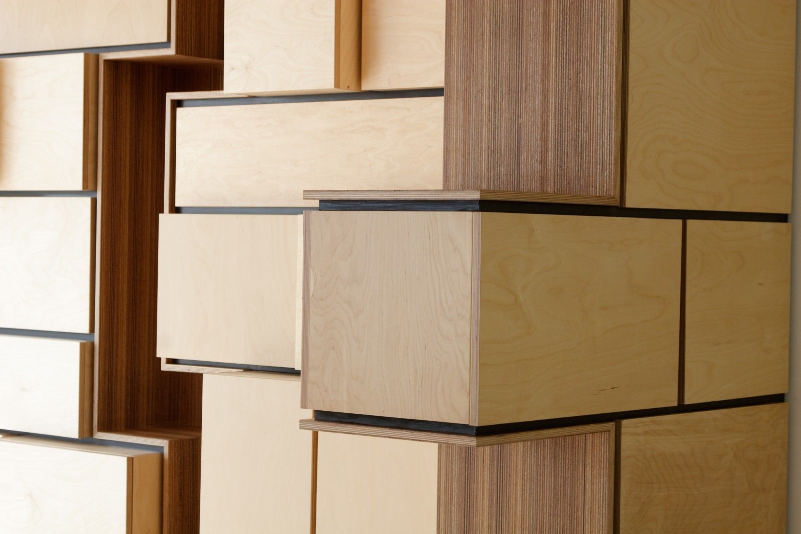 Detail van uitstekende kubusvormige kastfronten, met een gestreepte houten nis ertussen.