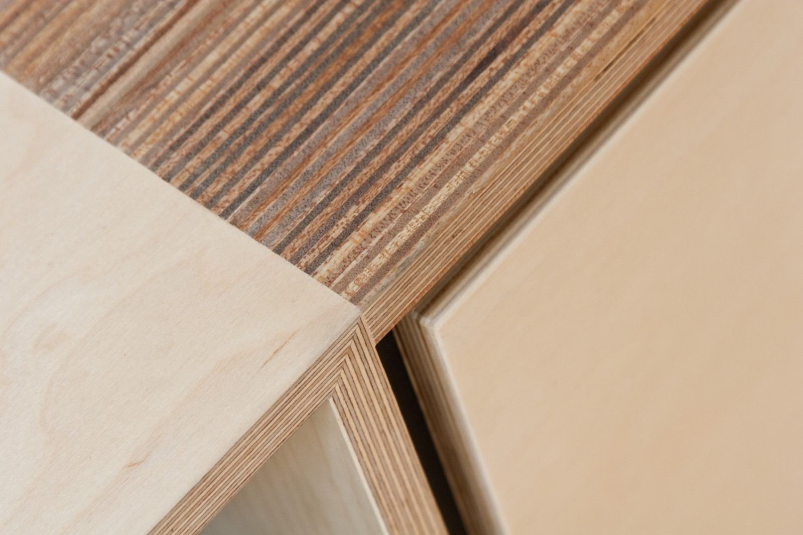Detail van een kastfront op een kier, naast een gestreepte houten rand.