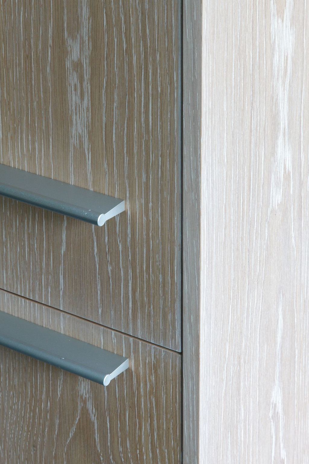 Detail van kastdeuren met metalen grepen in gewassen eikenfineer.