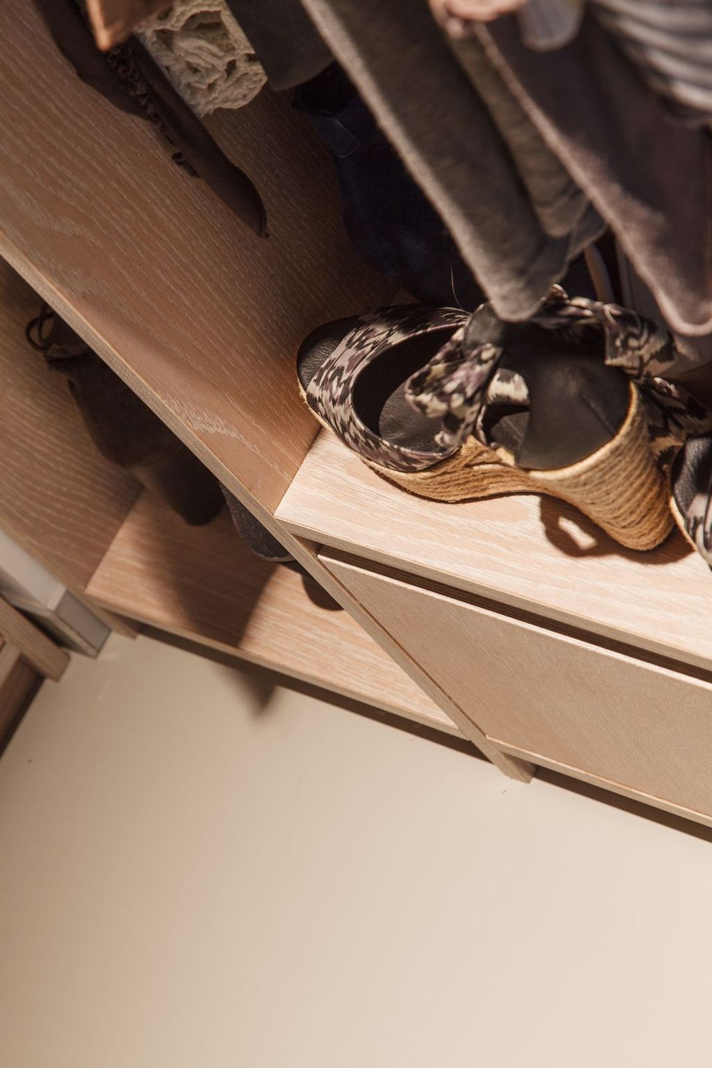 Detail van een lade in de inloopkast, met schoenen op de plank erboven.