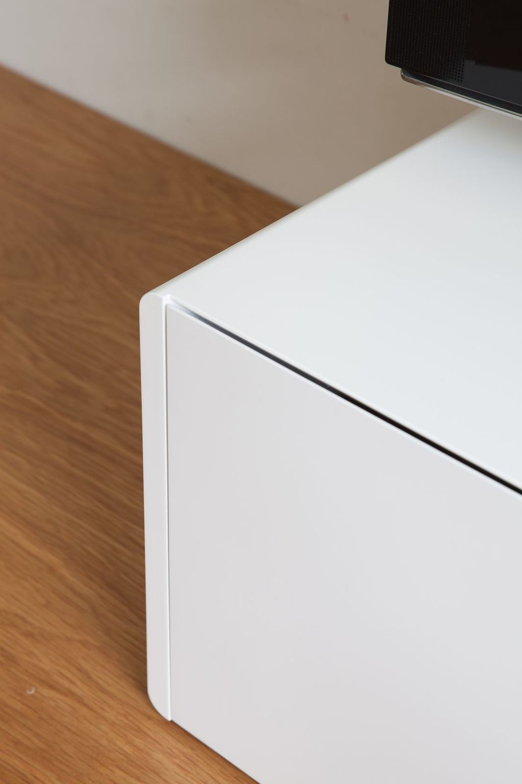 Close-up van de afgeronde hoek bovenop het witte dressoir.