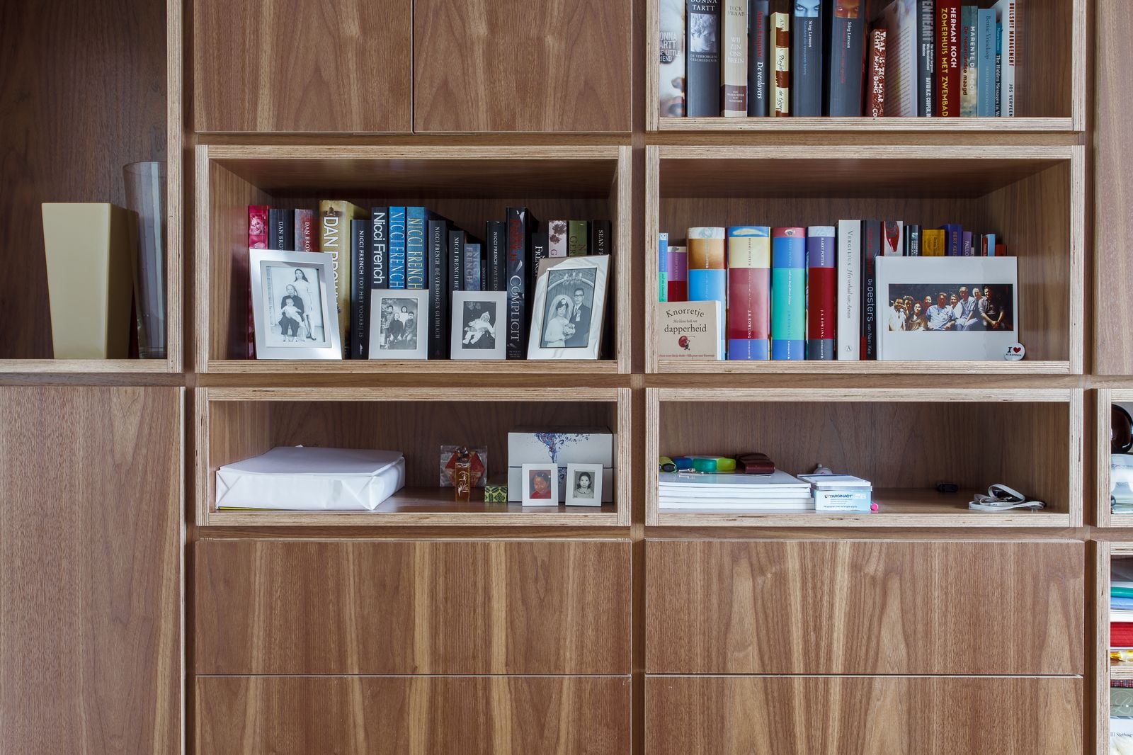Twee open vakken vol boeken en ingelijste familiefoto's.