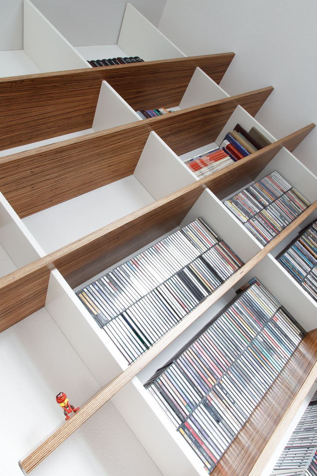 Van bovenaf gefotografeerde boekenplanken met een gestreepte houten binnenkant, gevuld met cd's.