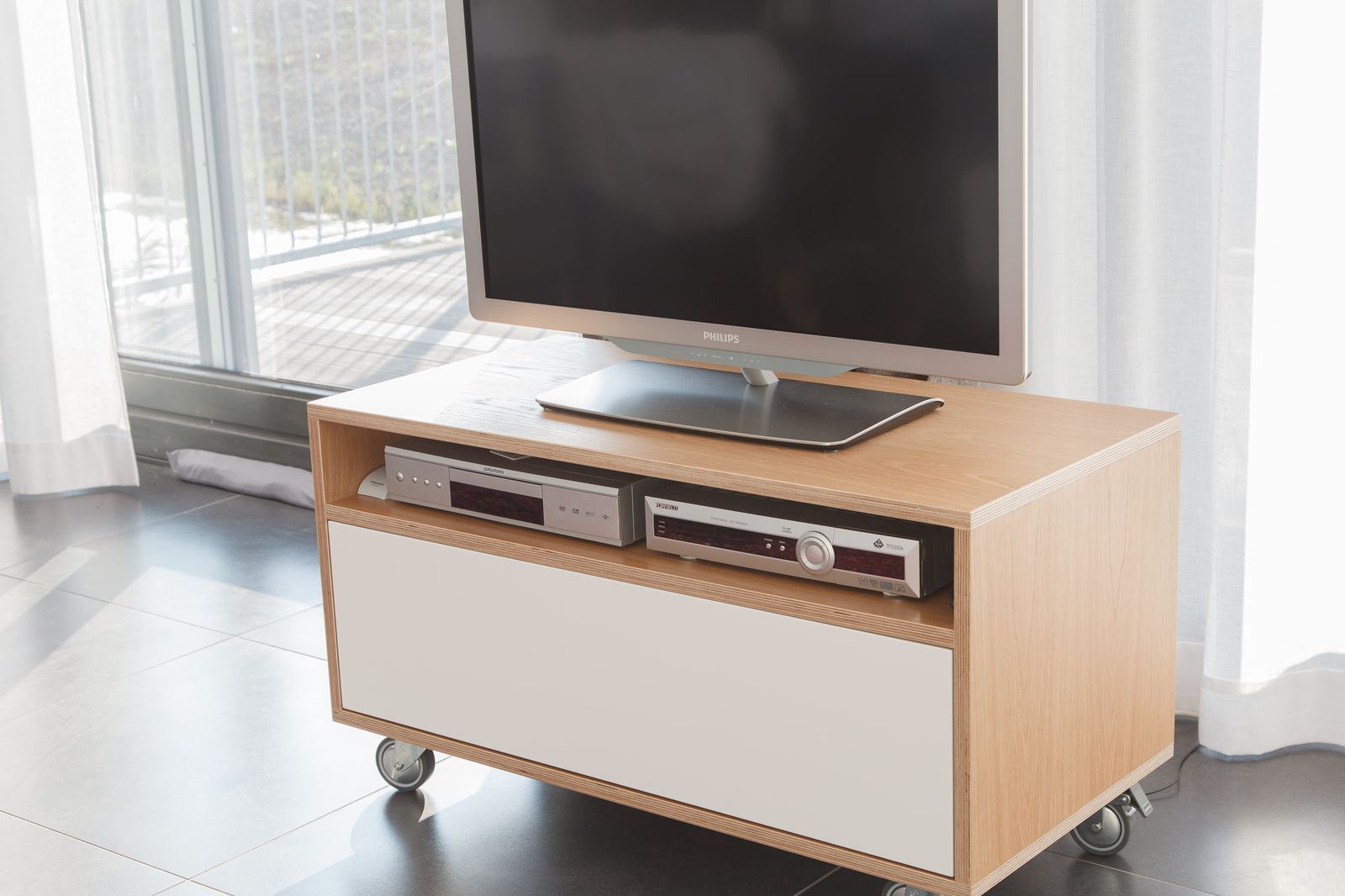 Tv-meubel op wielen met eiken behuizing en witte lade.