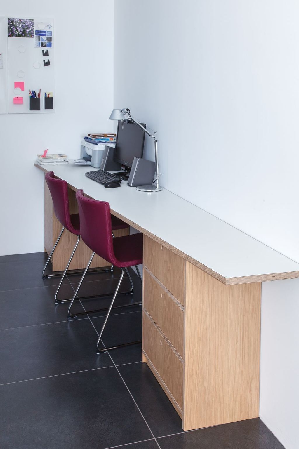 Lang bureau met wit blad en eiken ladenkasten aan weerszijden.