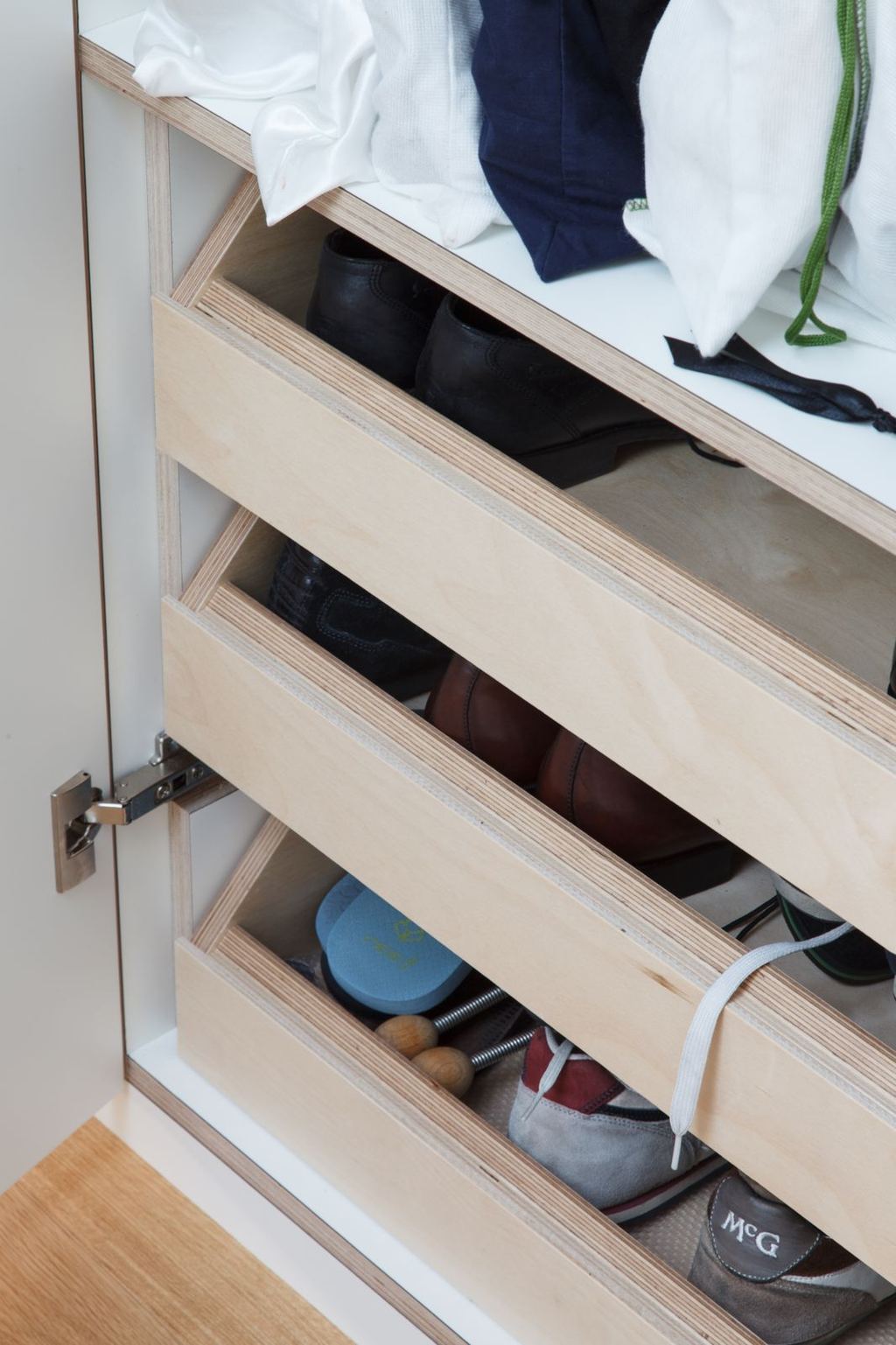 Uitgetrokken lade van de garderobekast gevuld met schoenen.
