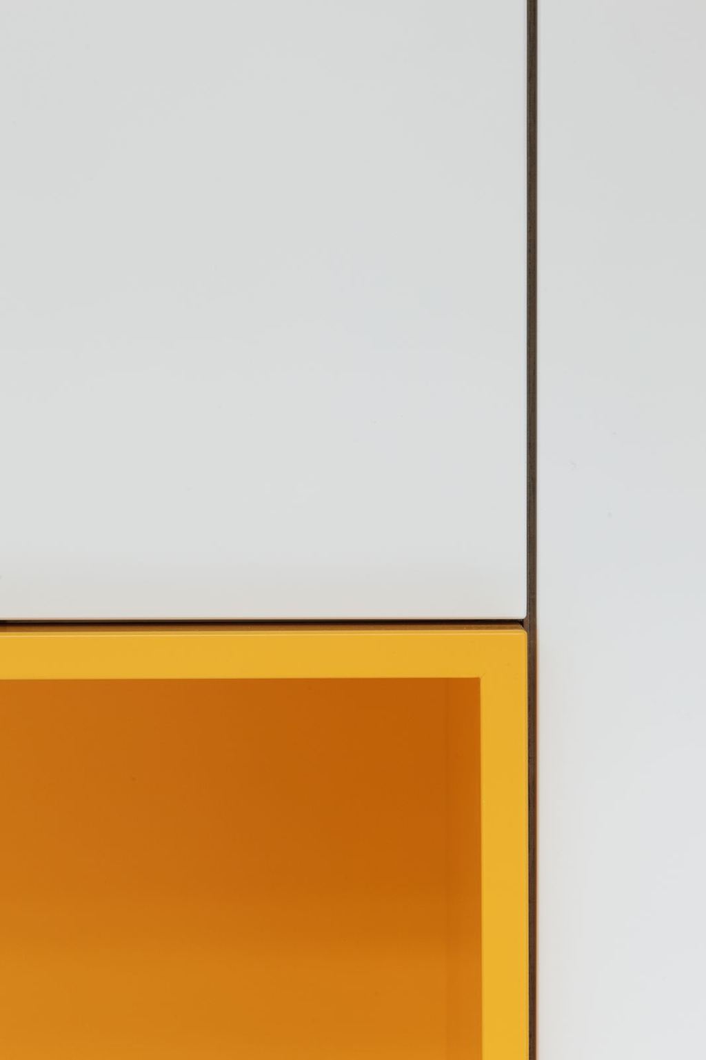 Detail van de hoek tussen een wit kastdeur en een gele opening.