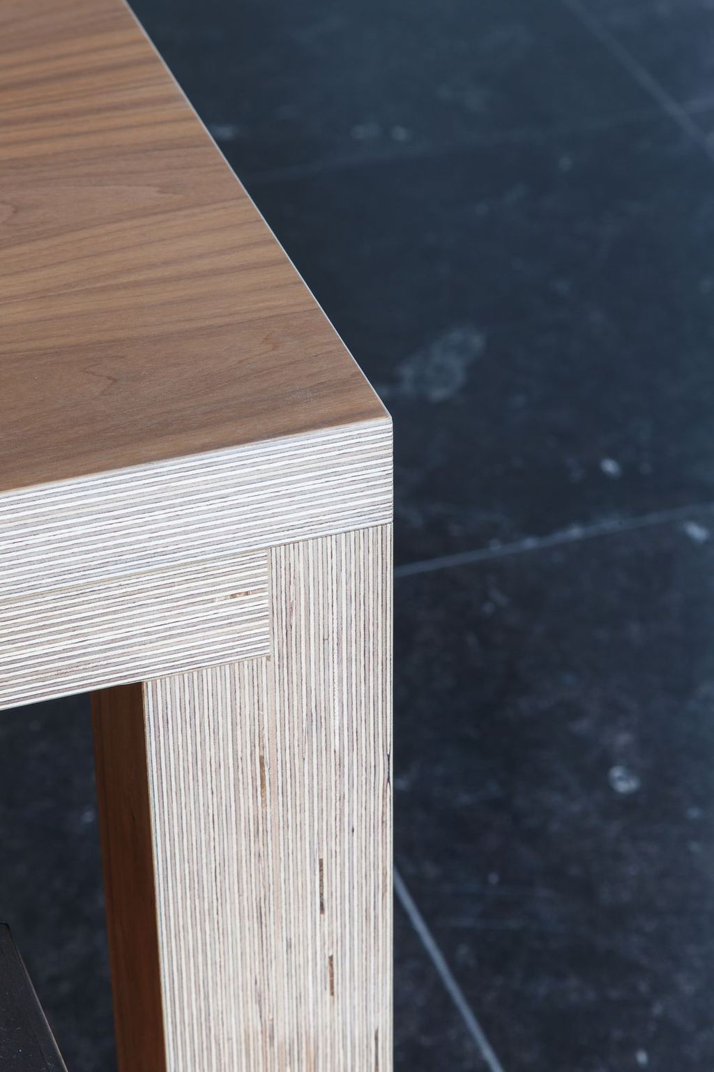 Detail van de fineerrand en houten poot van de eettafel.