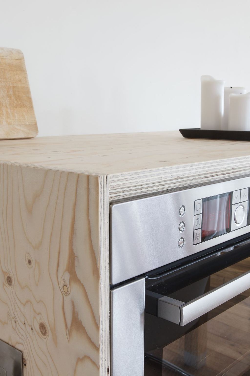 Detail van de houten omlijsting rond een ingebouwde oven, met een snijplank erboven.