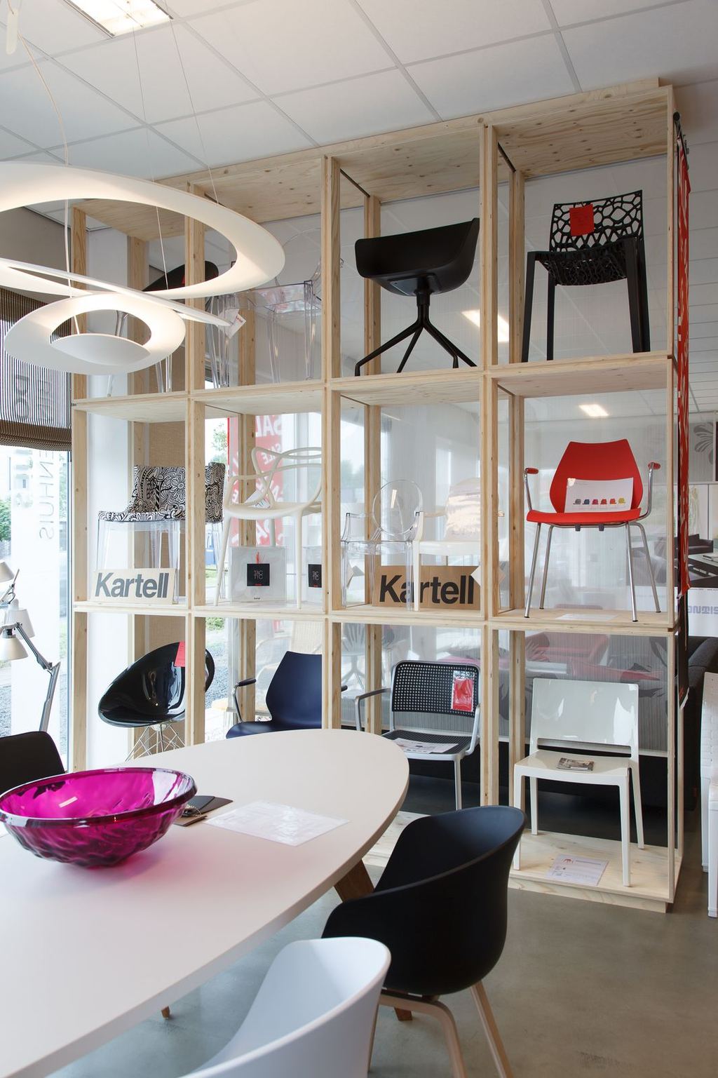 Wandvullend rek van massief hout, opgebouwd uit losse vakken met designstoelen erin.