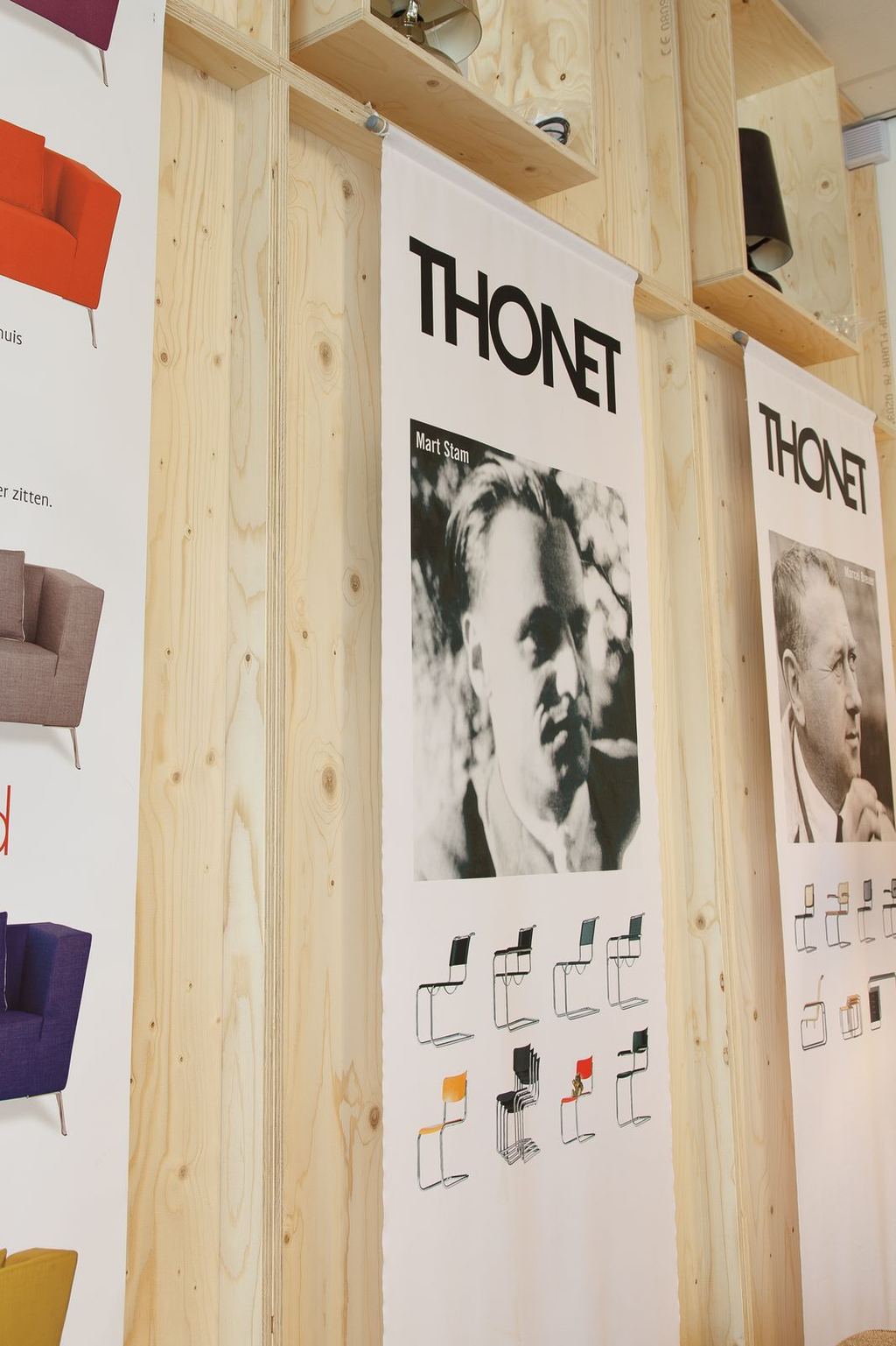 Detail van de vierkante nissen in het houten rek, met posters die ervoor hangen.