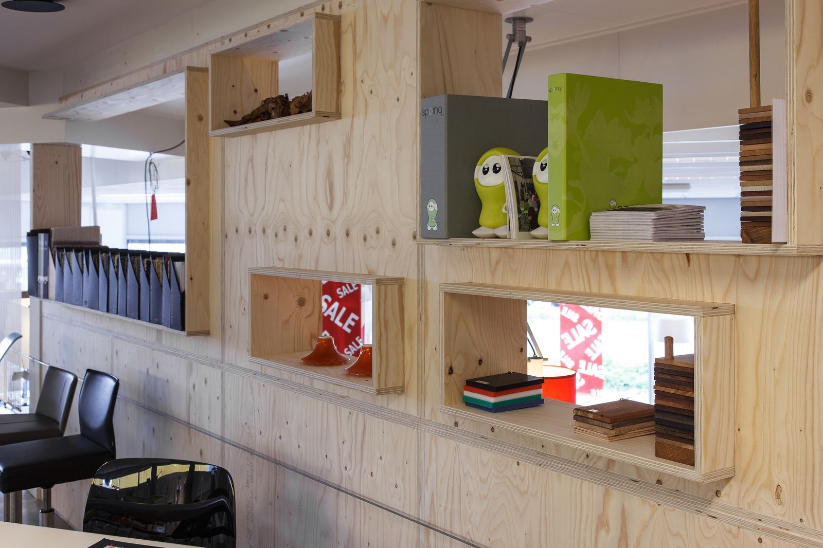Houten wandkast met losse rechthoekige nissen, gevuld met ordners en kleine objecten.