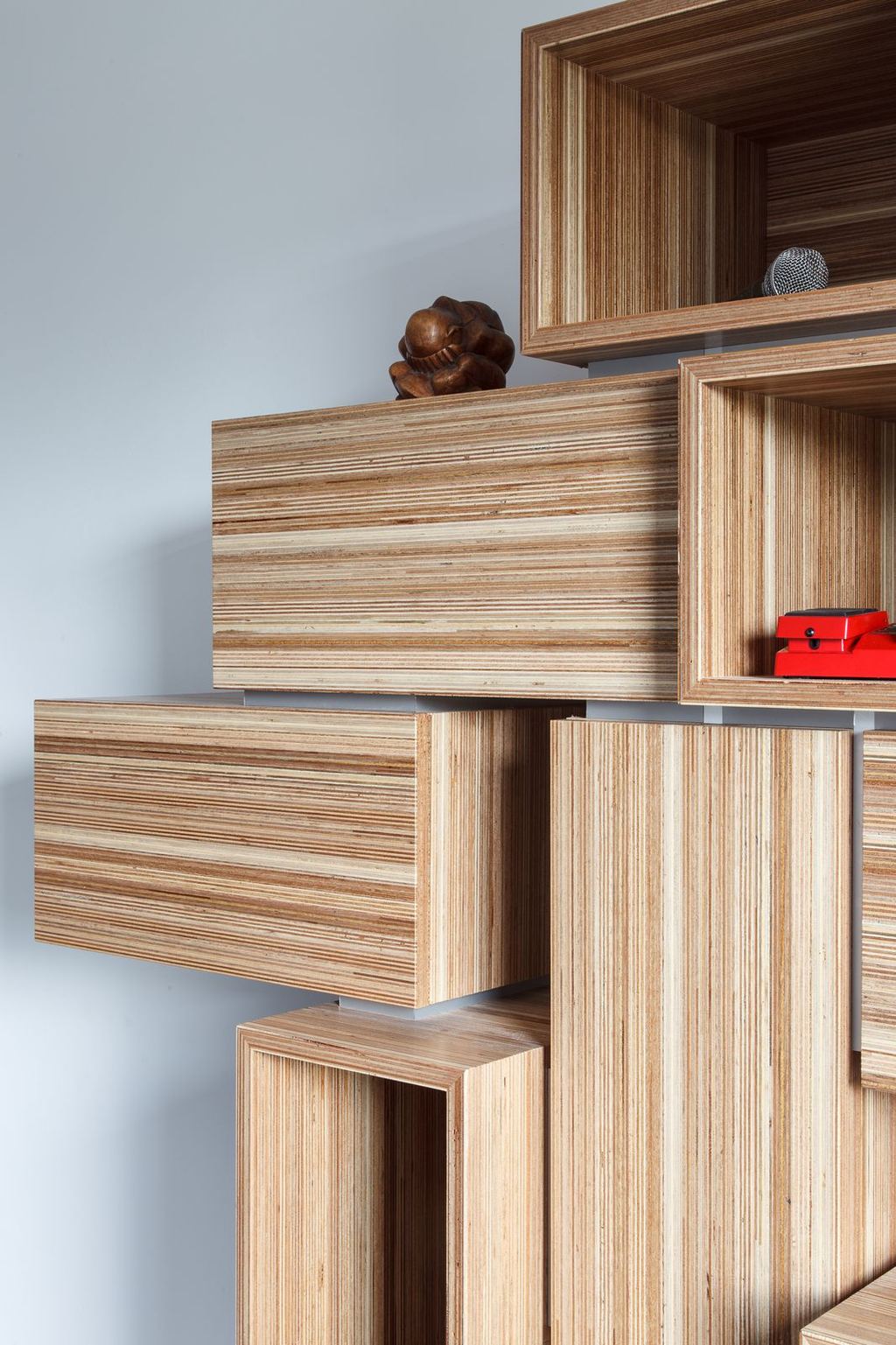 Detail van gestapelde houten vakken met een houten beeldje erop.
