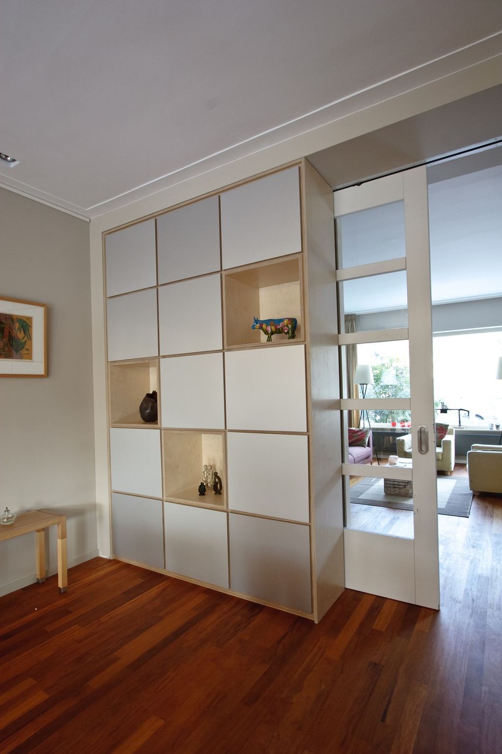 Kast als roomdivider met een raster van witte en open vakken.