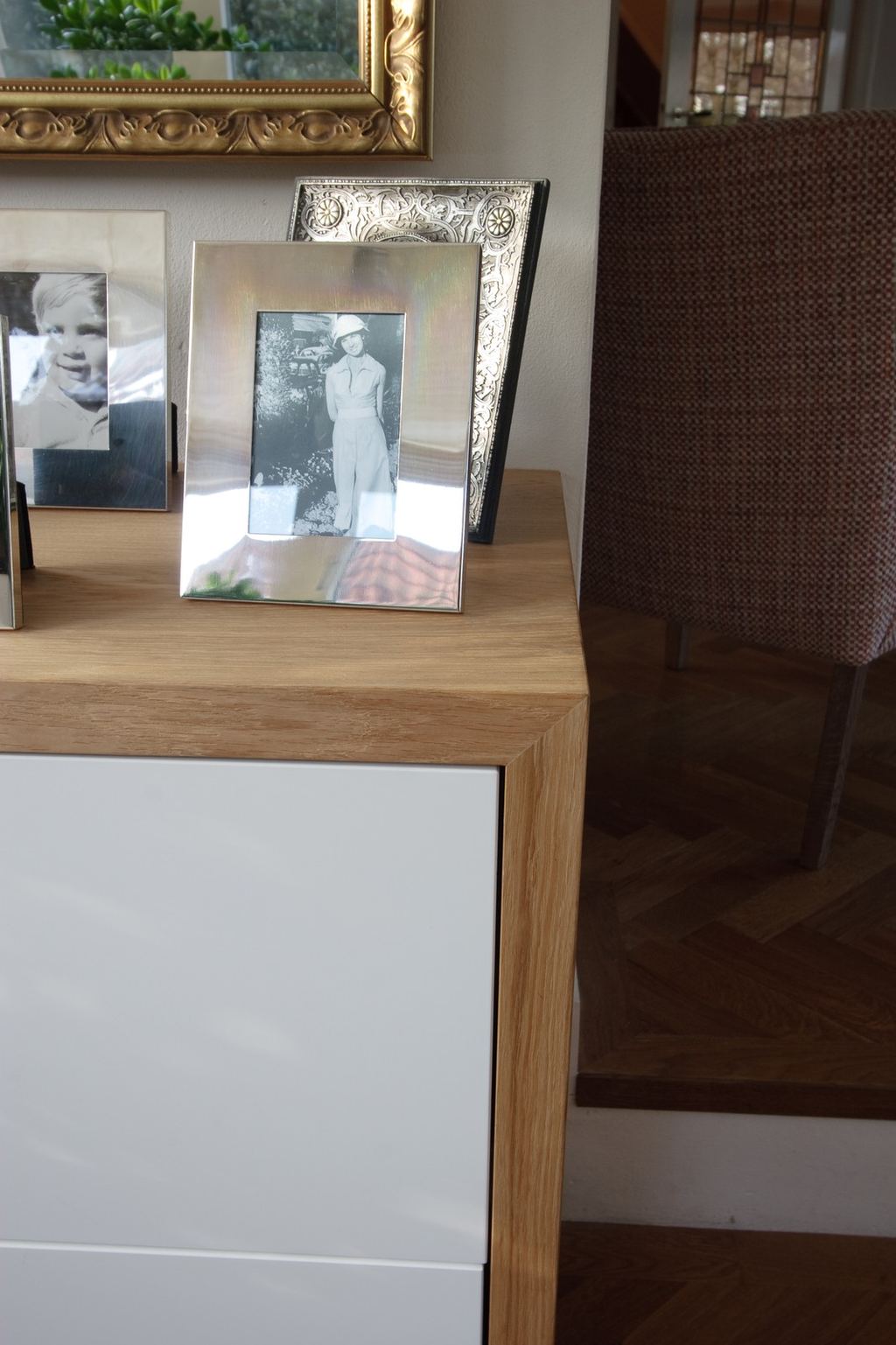 Detail van de houten rand en het witte front van een zwevende kast, gefotografeerd van bovenaf.