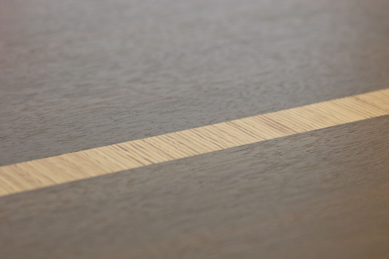 Detail van een lichte houten inlegstrook in een donker blad.