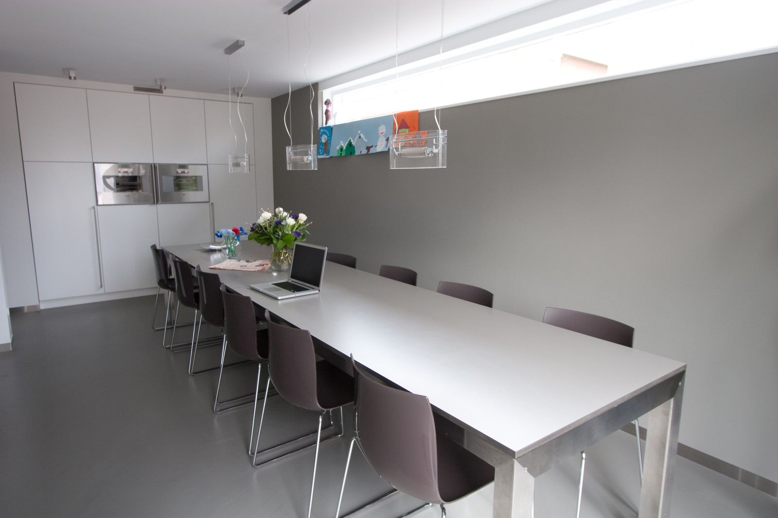 Lange keukentafel met HPL blad, omringd door stoelen.