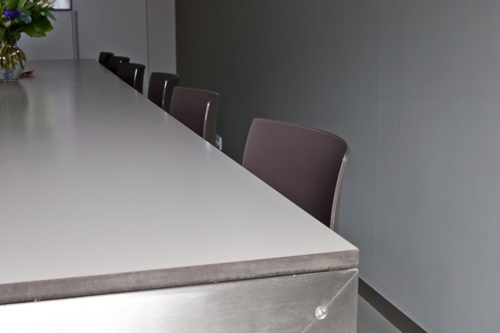 Lang HPL tafelblad met een rij stoelen ernaast.