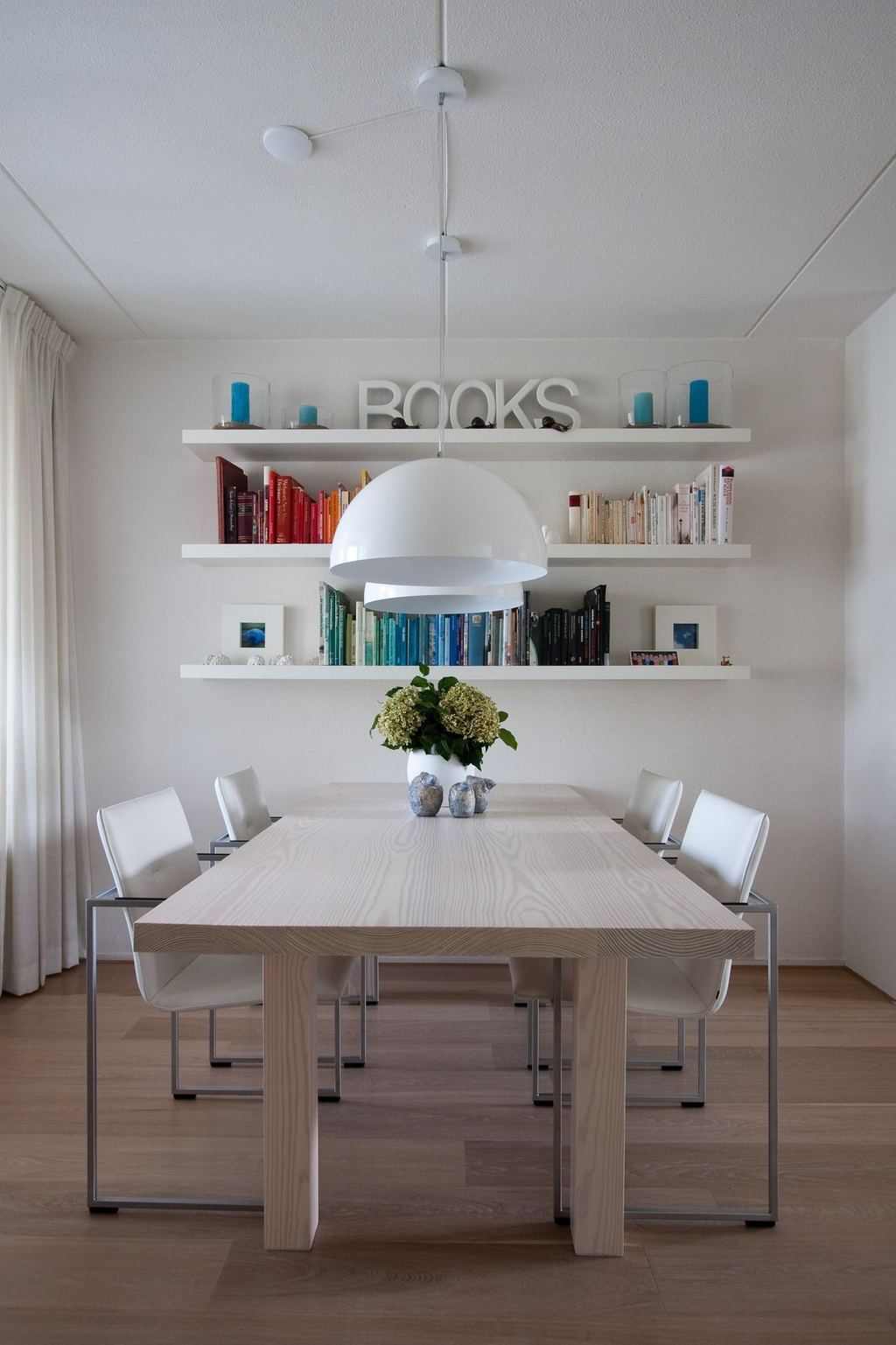 Rechthoekige tafel met een dik houten blad, met witte stoelen aan weerszijden.