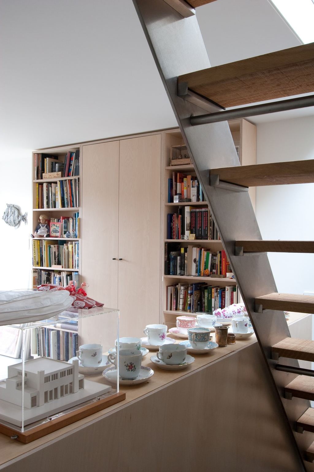 Wandvullende boekenkast met gesloten kastdeuren in het midden en open planken aan weerszijden.