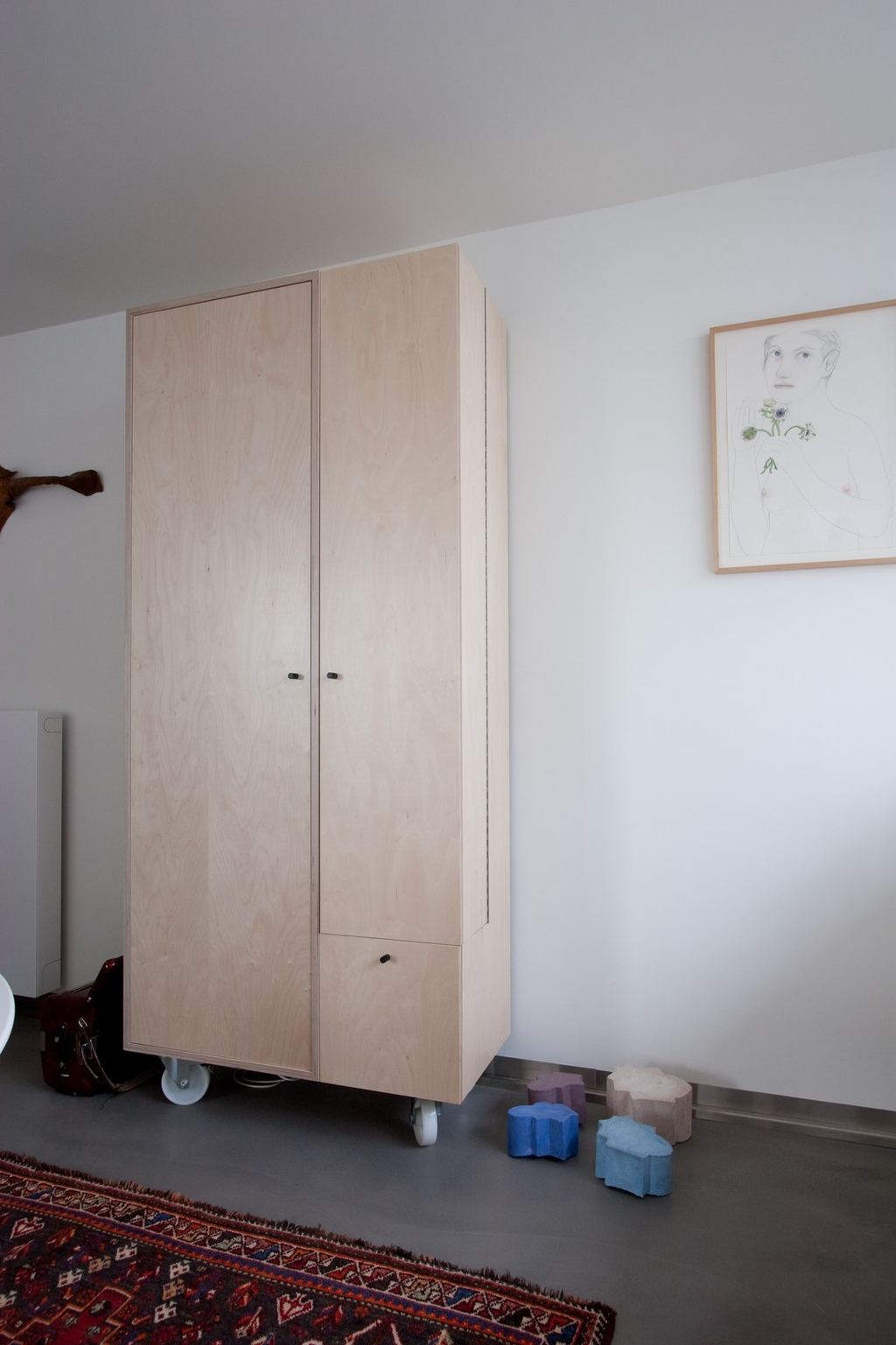 Kast van licht hout op wieltjes, met twee gesloten deuren naast elkaar.