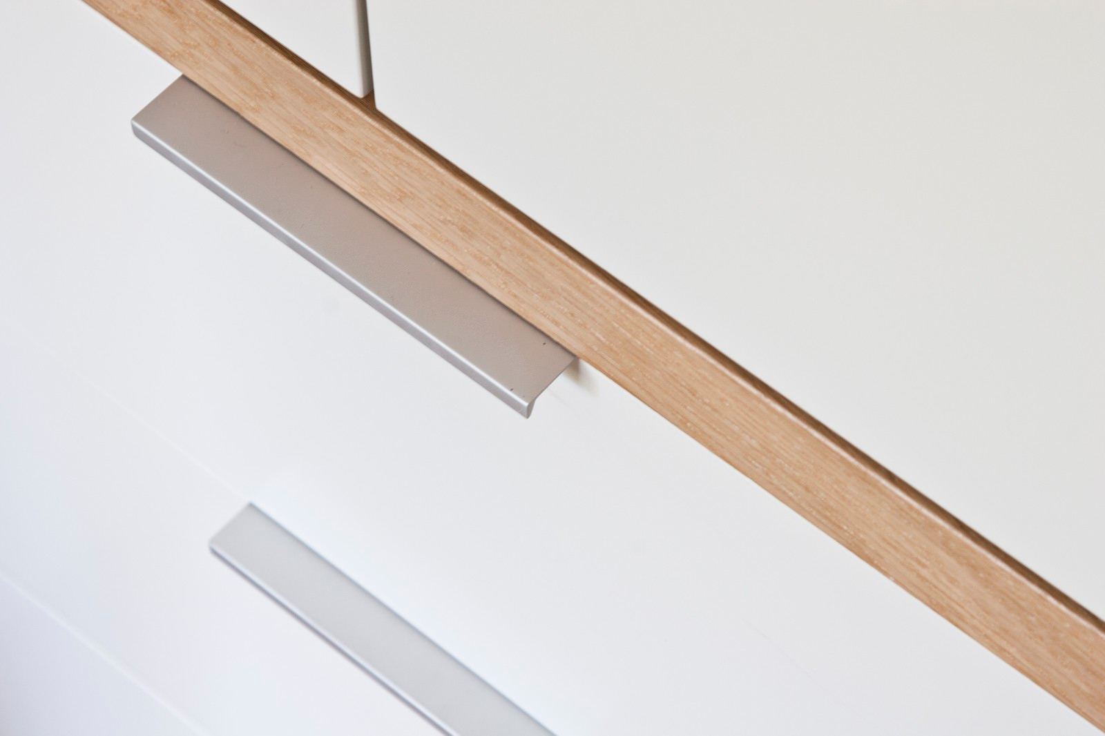 Detail van de eiken plank en aluminium greep van de kast.
