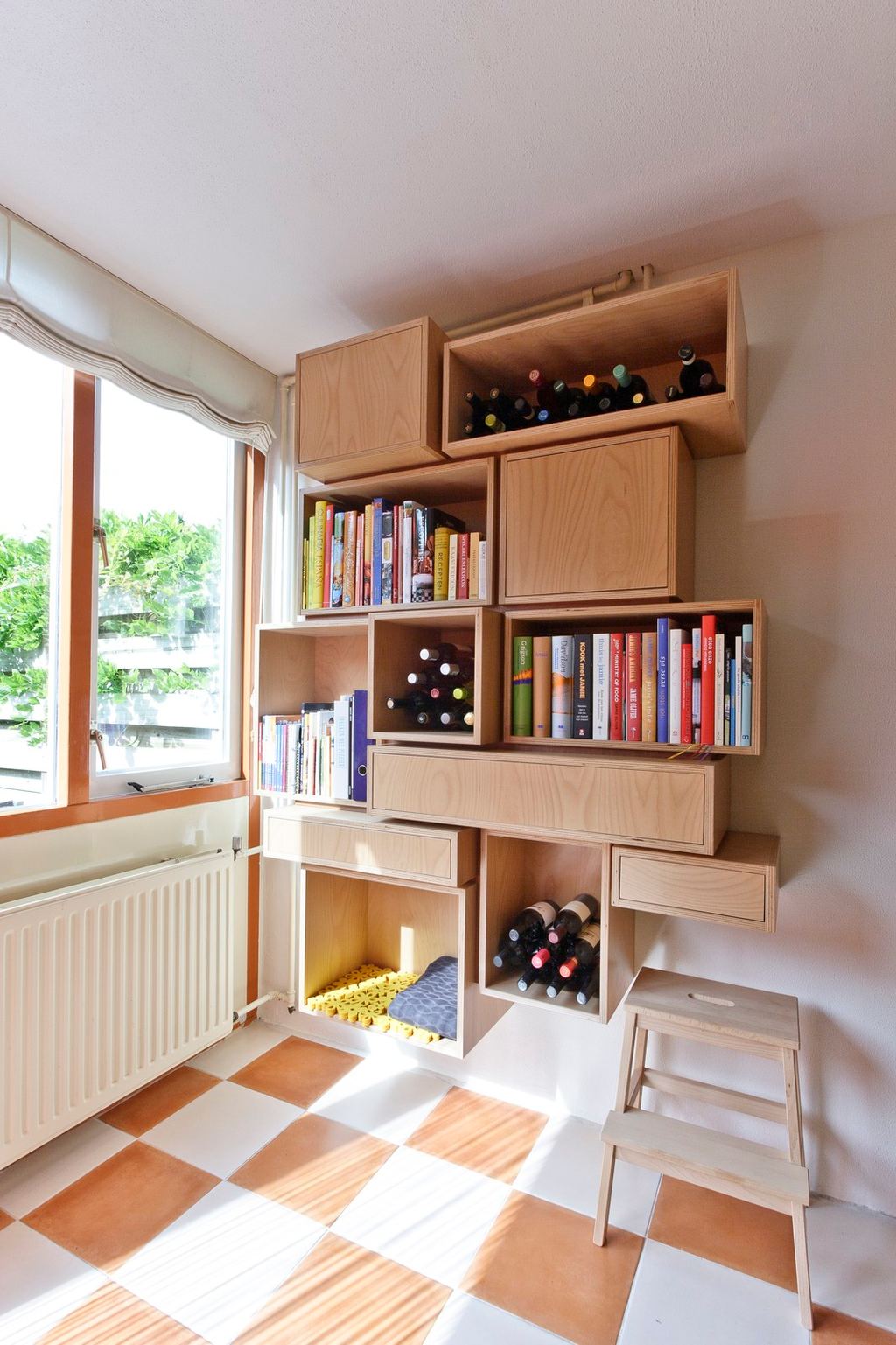 Stapeling van kastelementen in verschillende maten, met boeken en wijnflessen.